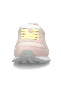 Scarpa da ginnastica rosa chiaro realizzata in materiali scamosciati e in rete, con dettagli bianchi, lacci gialli e una suola in gomma grigia con dettagli testurizzati.