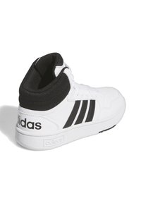 Białe sneakersy za kostkę z czarnymi akcentami, z trzema czarnymi paskami, siateczkowym kołnierzem i teksturowaną gumową podeszwą. Logo Adidas na pięcie.