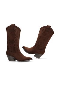 Par de botas de cowboy de ante marrón con costuras decorativas y tacones apilados en ángulo, mostradas una al lado de la otra sobre un fondo blanco.