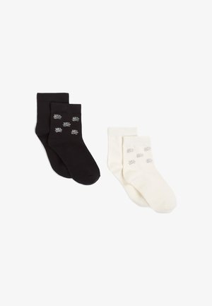 Calcetines tobilleros en blanco y negro, hechos de una tela suave y elástica, que presentan un sutil patrón decorativo en gris en cada par.