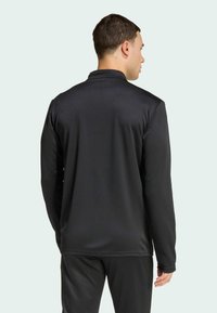 Μαύρος μακρυμάνικος μπλούζα με λεία υφή. Διαθέτει γιακά και επίπεδες ραφές, κατάλληλη για αθλητική ένδυση.