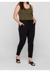 Olivgrön ribbad linne med knapprad, matchad med svarta tapered byxor med dragsko och ficköppningar samt platta svarta sandaler.