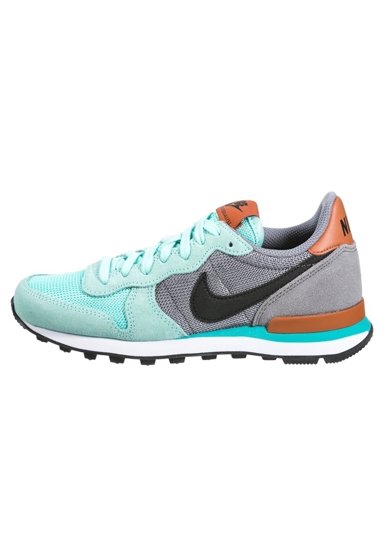 Zapatillas Nike con parte superior de malla y gamuza en verde menta, acentos grises, swoosh negro, pestaña del talón en naranja y detalles en azul verdoso en la suela.
