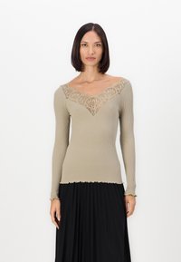 Hladký dlhý rukáv top v taupe farbe so širokým V-výstrihom a zložitými krajkovými detailmi. Zúžený lem a priliehavý strih pre elegantný vzhľad.