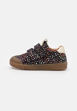 Czarny dziecięcy sneaker z wielokolorowymi metalicznymi groszkami, dwoma paskami na rzep, brązową gumową podeszwą i beżową pętelką na pięcie.