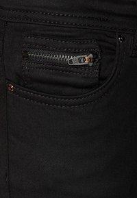 Melni džinsi no denim auduma, ar mazu rāvējslēdzēja kabatu, šuvēm un standarta priekšējo kabatu. Materiāls ir gluds, matēts.