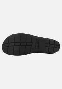 Black rubber shoe sole with deep tread pattern, featuring rectangular grooves and a branded logo. Flat design suitable for casual use.