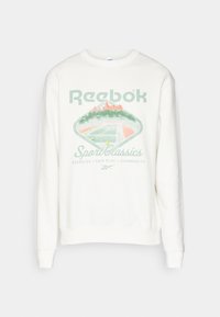 Felpa bianca con grafica di un campo da tennis verde e arancione, testo "Reebok Sport Classics" e parole "Esercizio, Fair Play, Comunità" sotto.