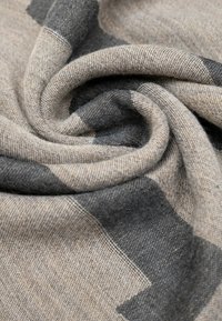 Tessuto beige e grigio con motivo a disegni, dalla texture morbida, caratterizzato da un design a vortice e blocchi di colore contrastanti. Materiale tessuto resistente.