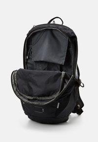 Sac à dos noir avec une grande ouverture, doté d'un intérieur gris, de plusieurs poches et d'une fermeture à glissière. Comprend des bretelles réglables et des accents en métal.