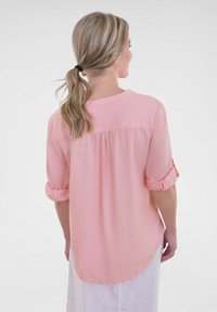 Light pink button-up shirt, semi-casual design, rolled sleeves, back yoke detail, and a curved hemline, made from airy fabric.