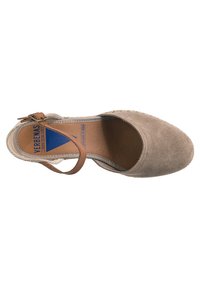 Sandalias de ante beige con puntas cerradas, tiras delgadas en el tobillo y plantilla en tono marrón. Presentan costuras decorativas alrededor de la suela.