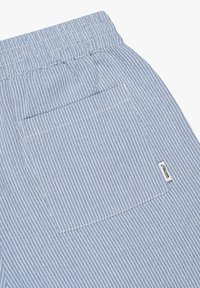Blauwe en witte gestreepte stof, met een elastische tailleband en een achterzak met een label. Gladde textuur, katoenen materiaal.
