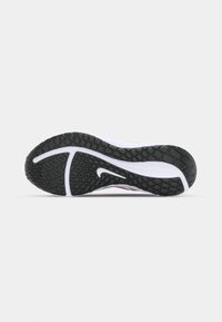 Bílá a růžová sportovní podrážka s texturovaným černým gumovým vzorkem, která obsahuje logo swoosh a zakřivené linie pro podporu a přilnavost.