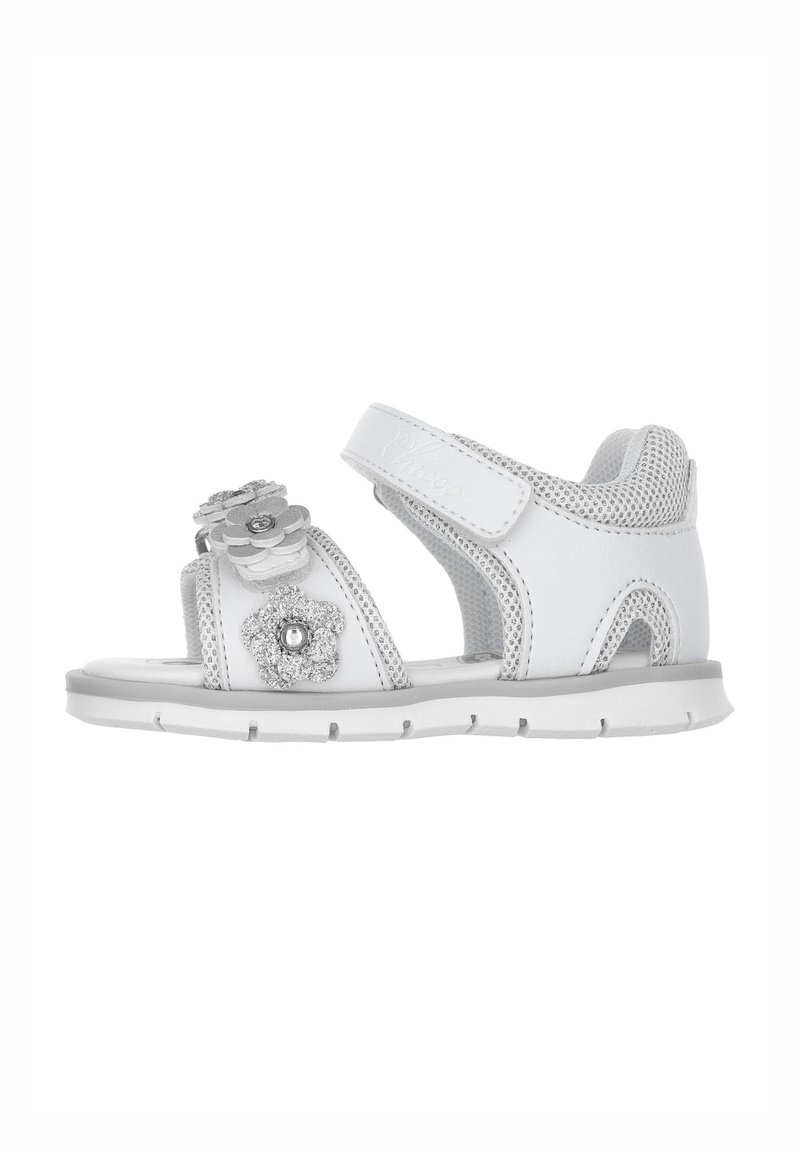 Sandalo bianco con decorazioni floreali, cinturino in Velcro, lati in rete e una suola imbottita. Presenta accenti argentati sui fiori.