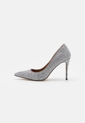 Czółenka na wysokim obcasie z ostrym noskiem, pokryte srebrno-czarną tkaniną o fakturze, z cienkim obcasem w kształcie stiletto i zaokrągloną sylwetką.