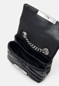 Černá kožená kabelka s prošívaným designem, stříbrným řetízkem a zapínáním na cvok. Uvnitř obsahuje více přihrádek.