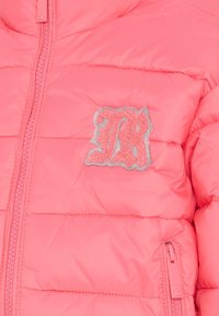 Różowa, puszysta kurtka z pikowanym wzorem, z zamkiem z przodu oraz teksturowaną naszywką z logo w różowym i srebrnym kolorze na lewej stronie klatki piersiowej.