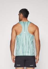 Sininen tank top vaaleansininen, jossa on pystyripustus, pyöreä kaula-aukko ja pidennetyt käsivarret. Valmistettu sileästä, kevyestä kankaasta. Yhdistetty mustiin shortseihin.