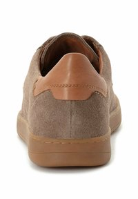 Braune Wildledersneaker mit einem tanfarbenen Lederakzent an der Ferse. Niedriges Profil, abgerundete Ferse und eine strukturierte Gummisohle.