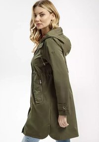 Oliwkowa kurtka przeciwdeszczowa z kapturem, z przednim zamkiem błyskawicznym, bocznymi kieszeniami i regulowanym pasem. Gładki materiał i luźny krój.