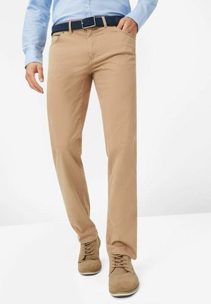 Beige straight-leg trousers with a smooth texture, featuring side pockets, a navy woven belt, and a classic cut. Paired with brown casual shoes.