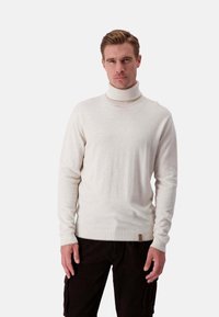 Cremfarbener Rollkragenpullover aus weichem Material mit langen Ärmeln, gerippten Bündchen und einem kleinen Lederelement am Saum.