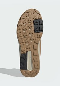 Hellbraun sportlicher Schuhsohle mit robustem Design, unterschiedlichen Profilmustern, schwarzen Akzenten und einer strukturierten Oberfläche für besseren Halt.