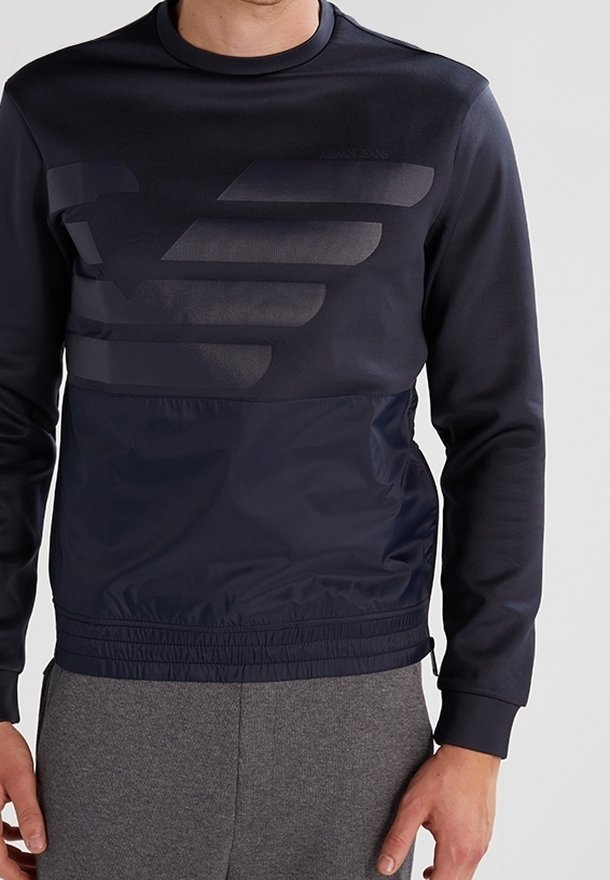 Námořnický modrý svetr s texturovanou horní částí, elegantním designem, elastickým pasem a velkým tištěným vzorem loga na přední straně.