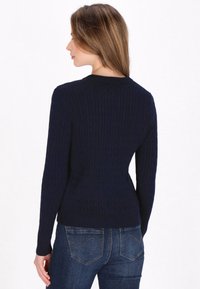 Navyblauwe gebreide trui met een ribbelstructuur, lange mouwen en een ronde halslijn. Glad materiaal met een aansluitende silhoutte.