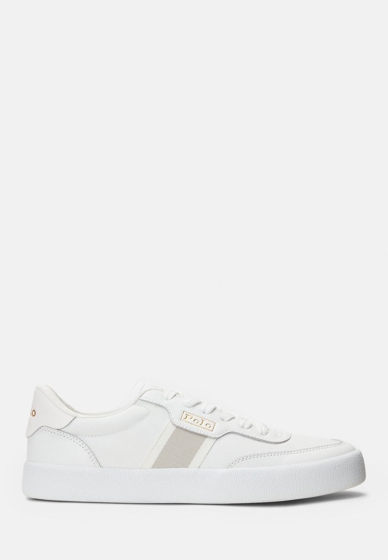 White sneaker with a textured rubber sole. Features soft canvas upper, beige accents, and a gold logo. Classic lace-up design.