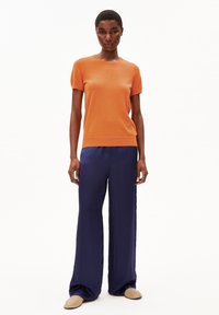 Oranje korte mouwen gebreide top gecombineerd met wijde marineblauwe broek. Soepele textuur, casual ontwerp met een getailleerde taille en een relaxte pasvorm.