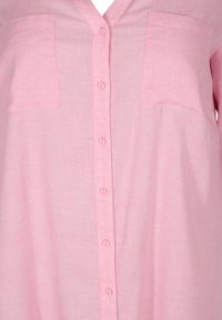 Camicia button-up rosa chiaro in tessuto testurizzato, con scollatura a V, due tasche sul petto e taglio dritto.