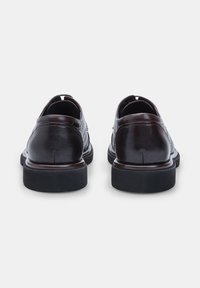 Chaussures en cuir marron avec une finition lisse, bout rond et semelles en caoutchouc noir basses. Présente des détails cousus le long des coutures.