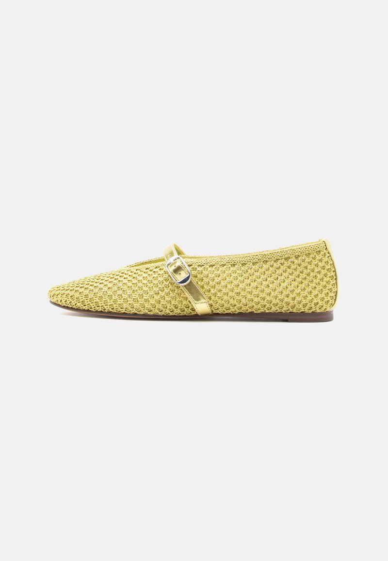 Chaussures plates en maille jaune avec un bout pointu et une fine lanière métallique dorée au milieu du pied, ornée d'une boucle. Semelle plate marron.
