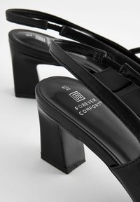 Sandalias negras de tacón con tacón cuadrado y parte superior de cuero liso y elegante. Con plantilla de marca y finas correas ajustables.