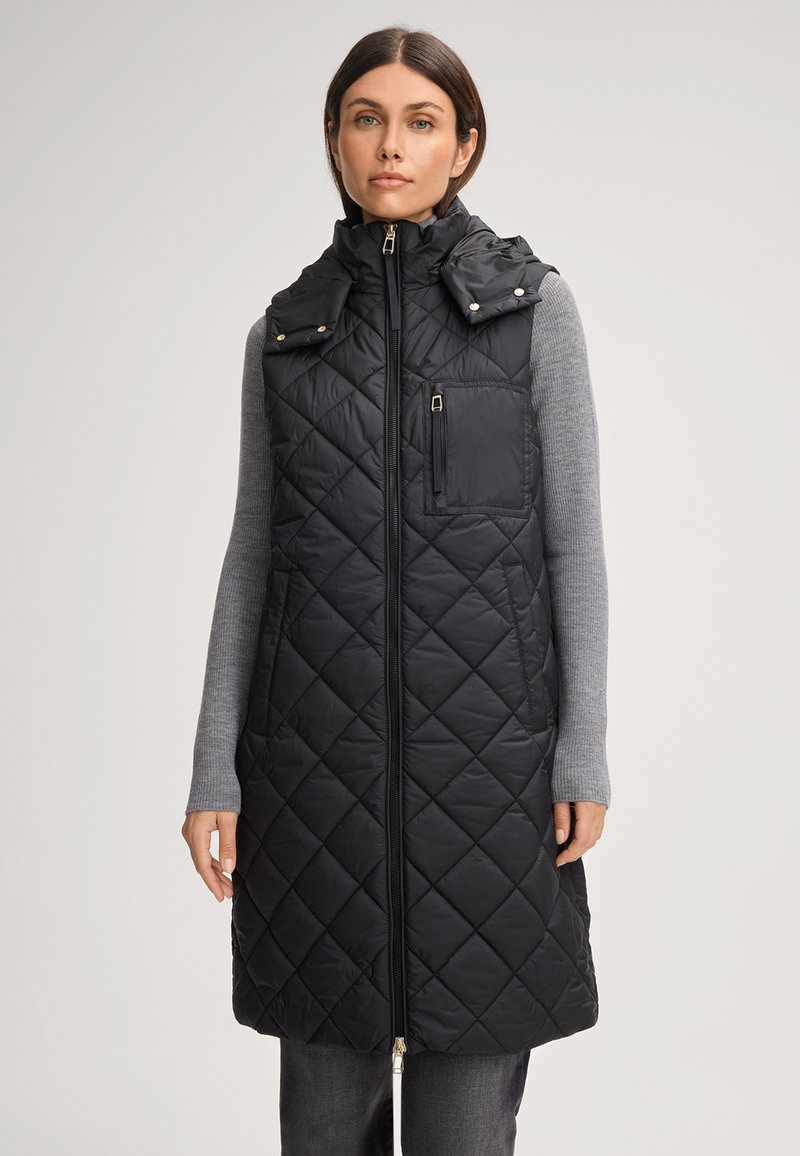 Schwarwestich-quilted langer Weste mit hohem Kragen, Reißverschluss und Vorder Tasche. Glatte Textur mit glänzenden Akzenten und kontrastierenden grauen Ärmeln.