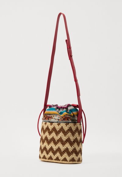 Woven straw bag with a zigzag pattern in brown and cream, featuring a colorful drawstring top and a red adjustable strap.