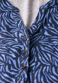 Camicia di tessuto blu navy con strisce a zebra azzurro chiaro, caratterizzata da un design con bottoni e un colletto. Morbida al tatto con motivi distintivi.