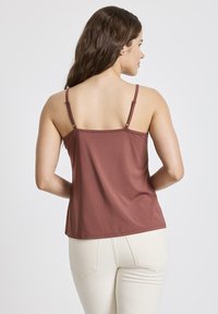 Maroon tank top with thin straps, smooth texture, and a relaxed fit. Back features minimalist design without patterns or details.