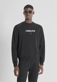 Sudadera negra con mangas raglán, que presenta el logotipo de texto "MORATO" en blanco y un pequeño emblema debajo. Hecha de una tela suave y texturizada.