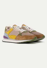 Sneaker multicolore con una combinazione di materiali in suede e mesh. I colori includono beige, giallo, verde e accenti viola su una suola bianca.