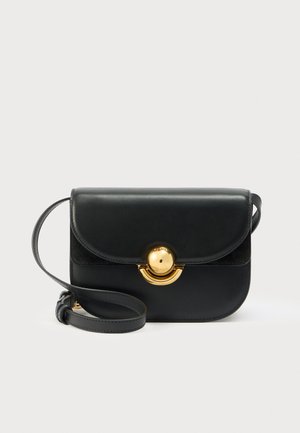 Bolso bandolera de piel negra con solapa curva y cierre redondo dorado, con una correa ajustable, sobre un fondo blanco liso.