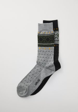 Zwei Paar gemusterte Socken mit einem Crew-Design, eine grau mit schwarzen und gelben Details, die andere schwarz mit grauen und gelben Akzenten, flach auf weißem Hintergrund ausgelegt.