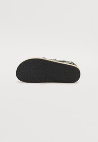Blue denim shoe with a textured black rubber sole, featuring a simple design and visible stitching details along the edges.