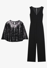 Sort paillet-cape top med rund halsudskæring og detalje med nøglehul på ryggen, parret med en ærmeløs sort jumpsuit med brede ben.