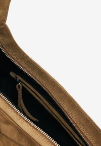 Borsa in suede marrone con una chiusura a zip, caratterizzata da una fodera nera e un tirante in pelle. L'interno presenta diversi scomparti.
