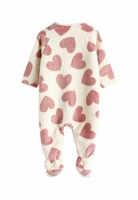 Fleece Baby Overall in Creme mit rosa Herzmustern. Verfügt über lange Ärmel und ein fußloses Design, mit gerippten Bündchen und Kragen.