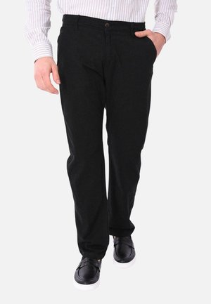 Pantaloni di cotone neri con vestibilità dritta, caratterizzati da una chiusura con bottone, tasche laterali e abbinati a scarpe nere slip-on.