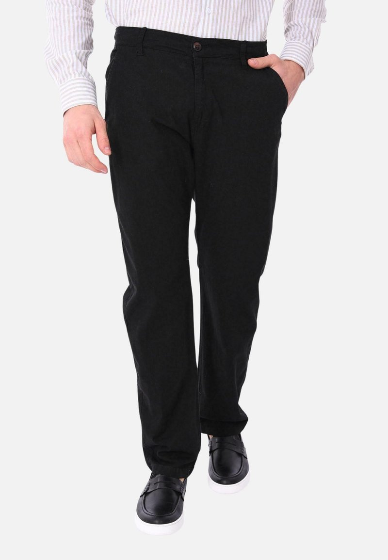 Pantaloni di cotone neri con vestibilità dritta, caratterizzati da una chiusura con bottone, tasche laterali e abbinati a scarpe nere slip-on.